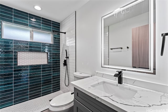 bathroom featuring vanity, toilet, and tiled shower