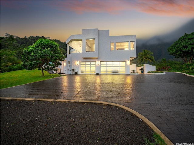 contemporary home with a front yard, stucco siding, decorative driveway, and an attached garage