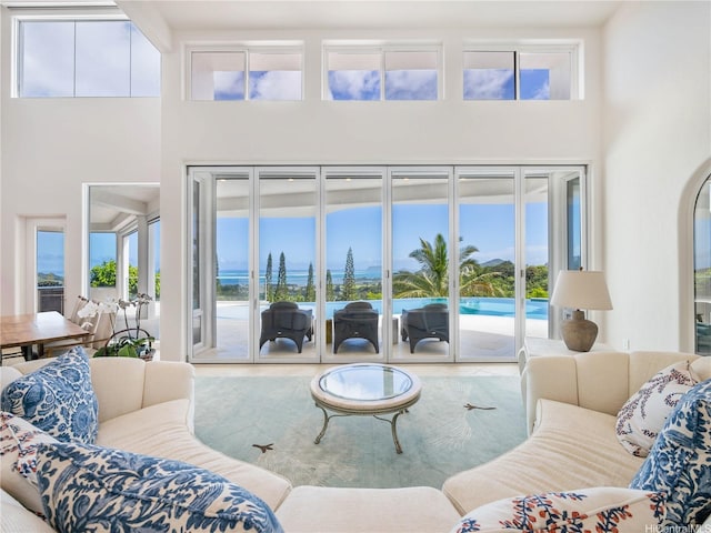 living area with a high ceiling, a water view, and plenty of natural light