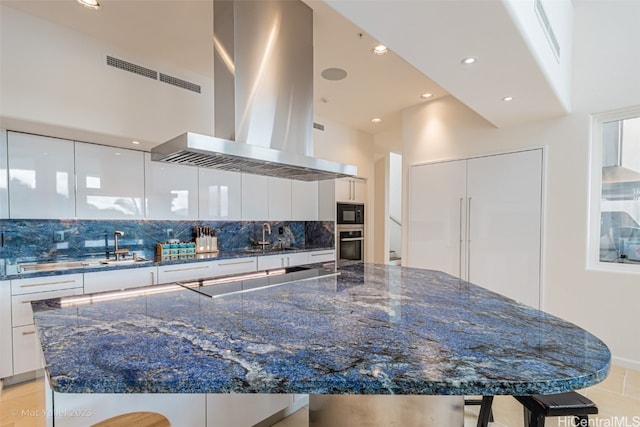 kitchen with decorative backsplash, a kitchen breakfast bar, range hood, black appliances, and white cabinetry