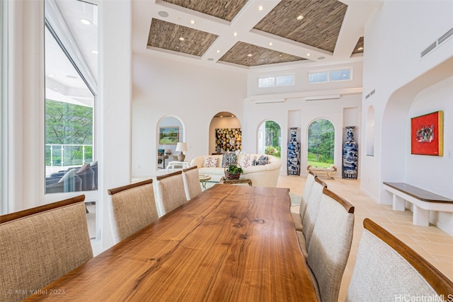 unfurnished dining area featuring coffered ceiling, beamed ceiling, and a high ceiling