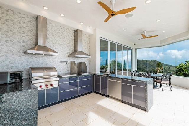 kitchen featuring dark stone countertops, wall chimney range hood, dishwasher, and kitchen peninsula