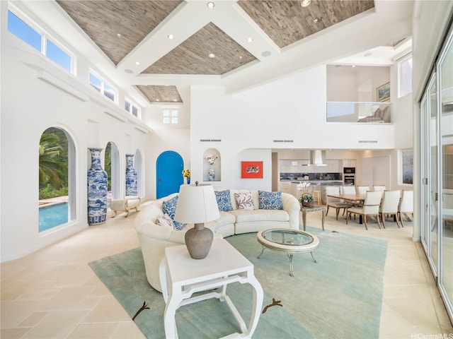 living room with recessed lighting, beamed ceiling, a healthy amount of sunlight, and a high ceiling