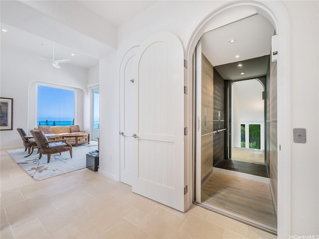 hallway with light tile patterned flooring, recessed lighting, arched walkways, and baseboards