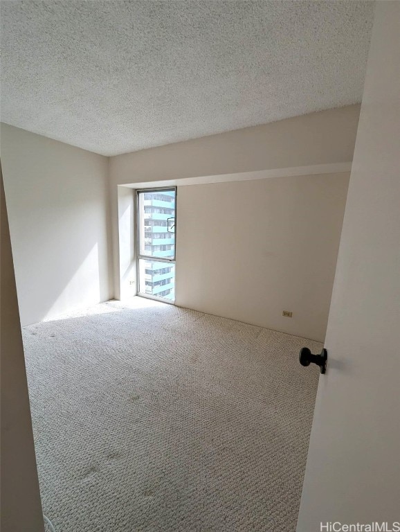 carpeted spare room with a textured ceiling