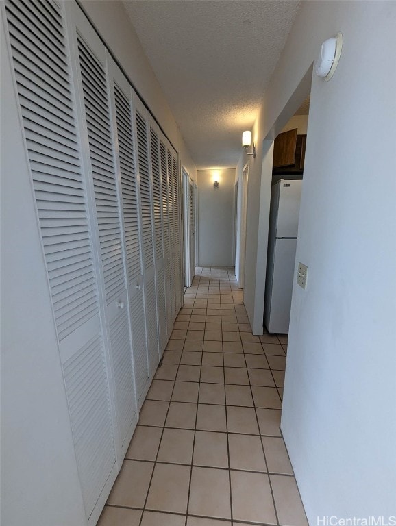 hall featuring a textured ceiling and light tile patterned flooring