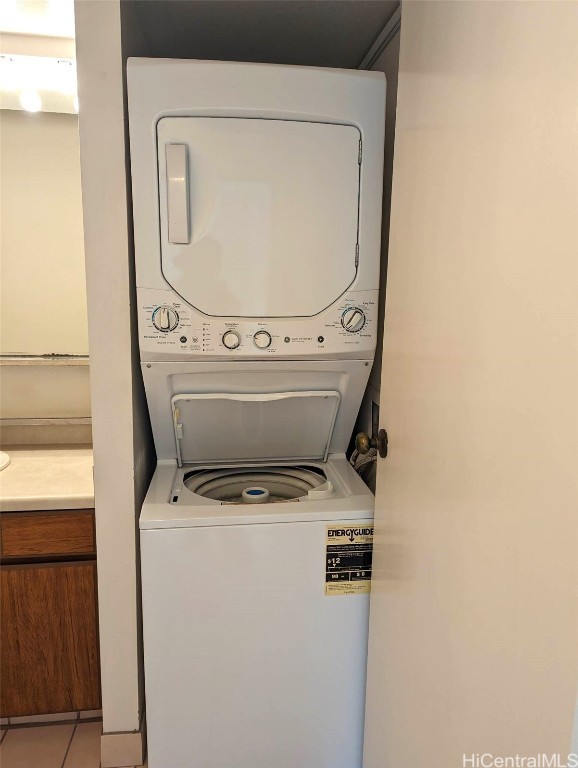 clothes washing area with light tile patterned flooring and stacked washer / dryer