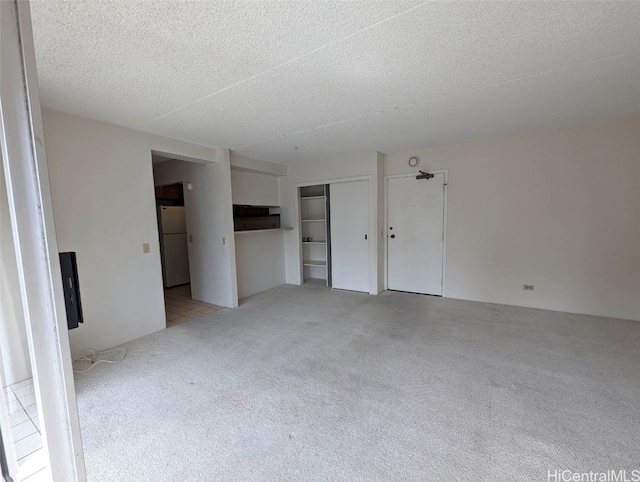 unfurnished living room with a textured ceiling and light colored carpet