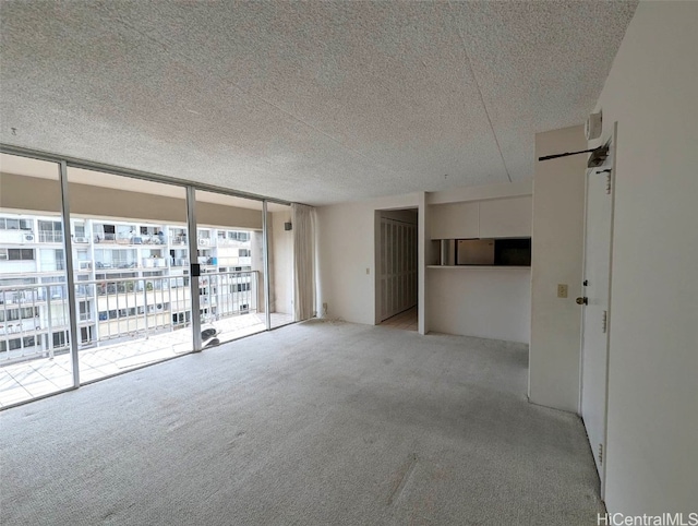 unfurnished room featuring a textured ceiling, light colored carpet, and expansive windows