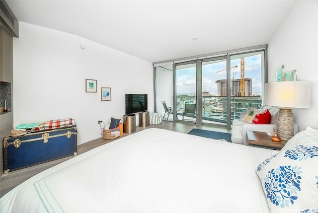 bedroom with access to exterior, a wall of windows, and hardwood / wood-style floors