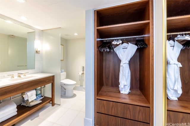 bathroom with toilet, sink, and tile patterned flooring