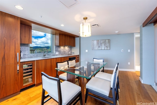 dining room featuring light hardwood / wood-style floors, wine cooler, and sink