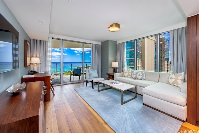 living room featuring floor to ceiling windows, hardwood / wood-style flooring, and a water view