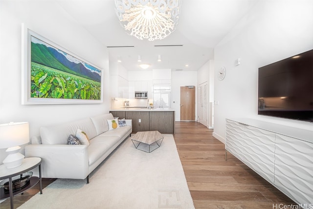 living room featuring a chandelier and light wood-type flooring