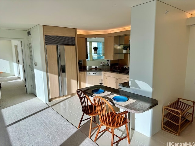 kitchen with sink, dishwasher, light tile patterned flooring, and paneled built in refrigerator