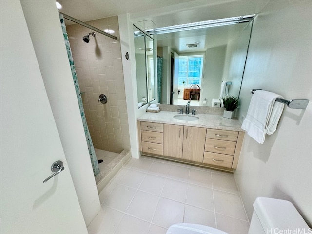 bathroom with toilet, vanity, a tile shower, and tile patterned floors