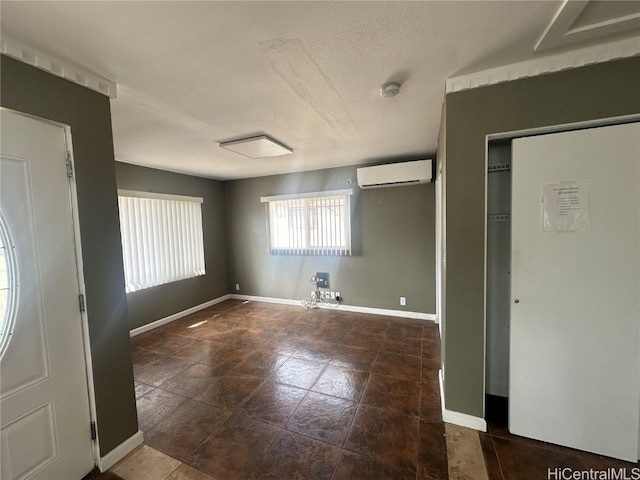 interior space with an AC wall unit and a textured ceiling