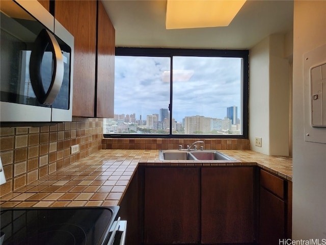 kitchen with tile countertops, range, sink, and tasteful backsplash