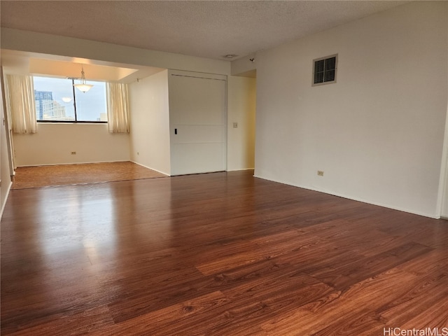 empty room featuring a textured ceiling and dark hardwood / wood-style flooring