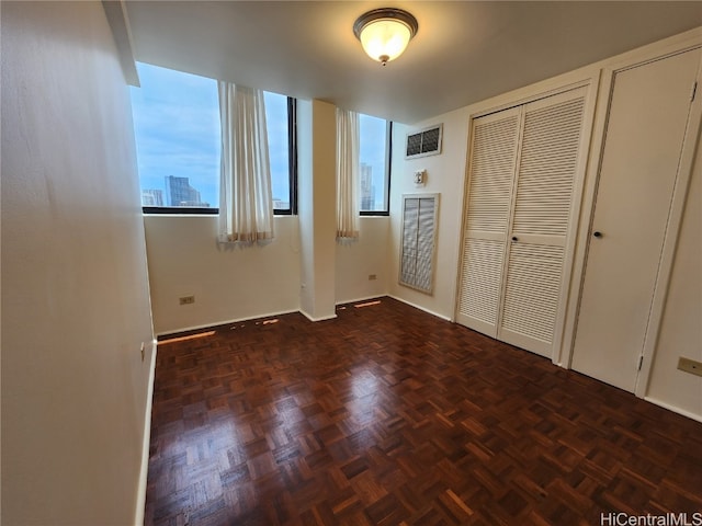 unfurnished bedroom featuring multiple closets, multiple windows, and dark parquet flooring