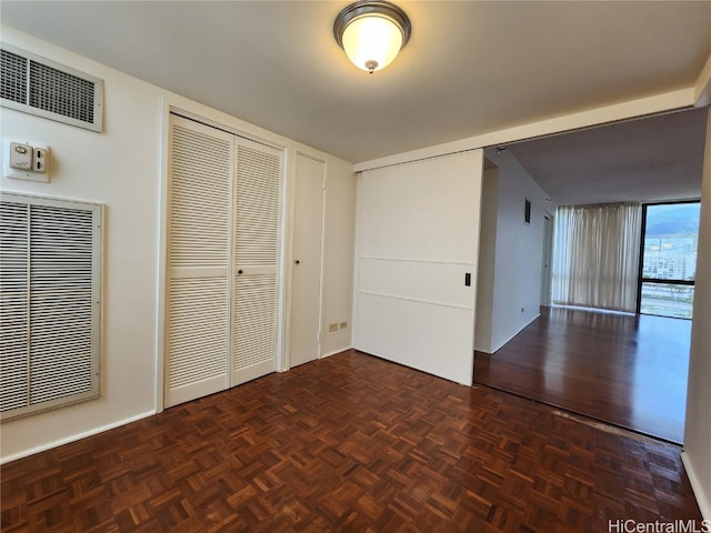 unfurnished bedroom featuring dark parquet floors and multiple closets