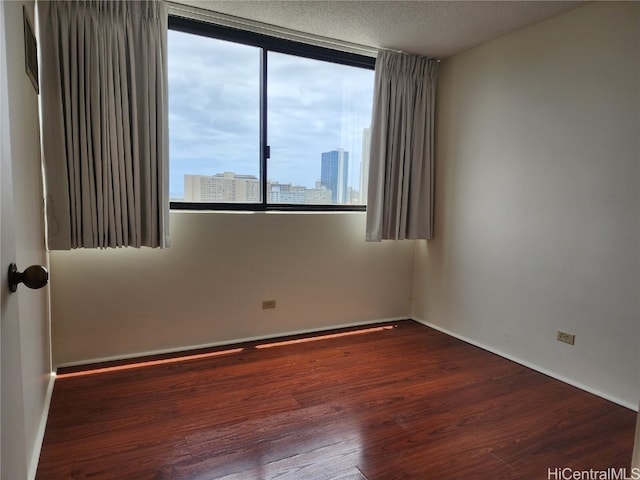 unfurnished room with a textured ceiling and dark hardwood / wood-style floors