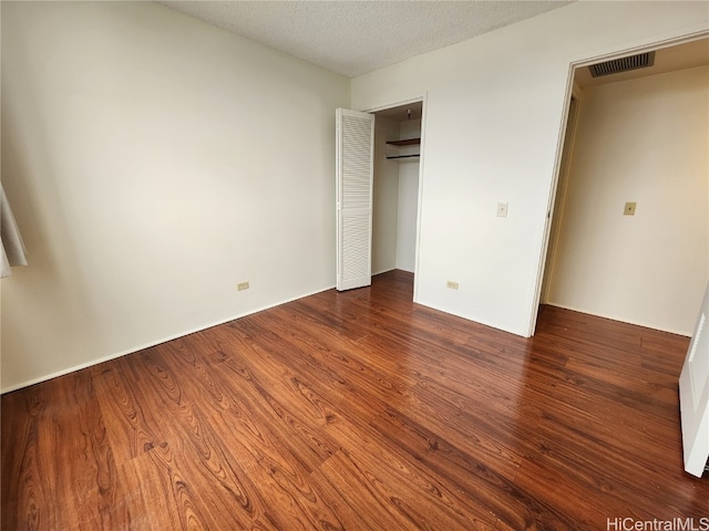 unfurnished bedroom featuring a textured ceiling and dark hardwood / wood-style floors