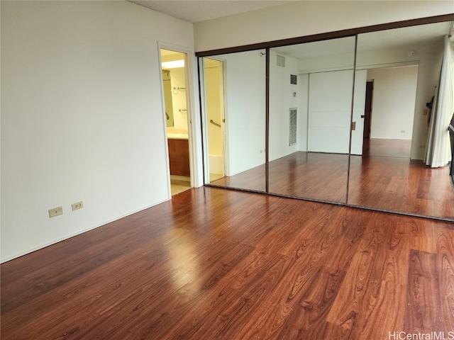 unfurnished bedroom featuring a closet and hardwood / wood-style floors