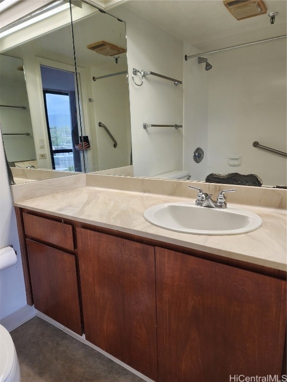 bathroom featuring vanity, toilet, and walk in shower