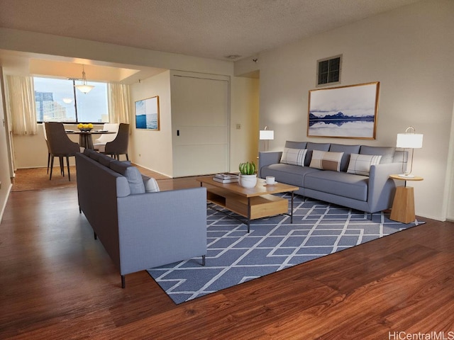 living room with a textured ceiling and dark hardwood / wood-style floors