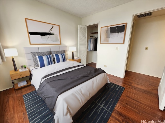 bedroom featuring a closet, a textured ceiling, and dark hardwood / wood-style flooring