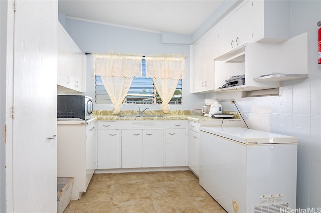 kitchen featuring sink, fridge, and white cabinets