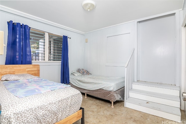 bedroom with wood walls, ornamental molding, and light colored carpet