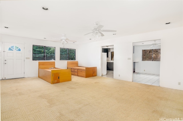 unfurnished living room with light colored carpet and ceiling fan