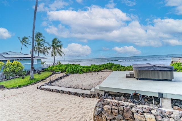 view of patio with a hot tub and a water view