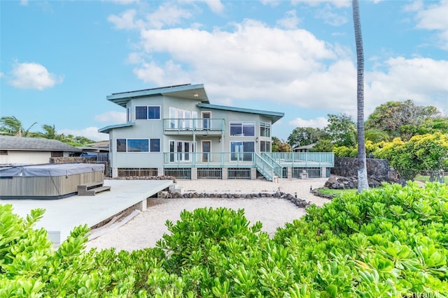 rear view of property featuring a balcony and a hot tub