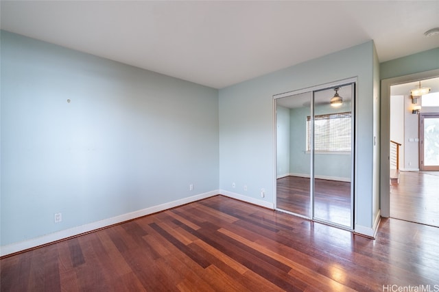 unfurnished bedroom with a closet, a chandelier, and dark hardwood / wood-style floors