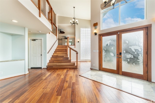 entryway featuring french doors, a towering ceiling, a chandelier, and hardwood / wood-style floors