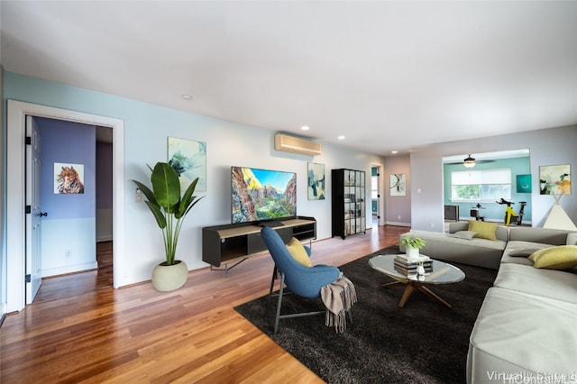 living room featuring a wall mounted air conditioner, hardwood / wood-style flooring, and ceiling fan