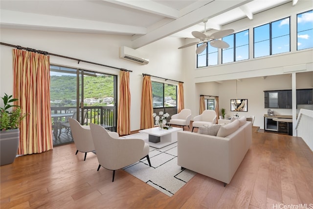 living room with a wall unit AC, ceiling fan, hardwood / wood-style flooring, high vaulted ceiling, and beamed ceiling