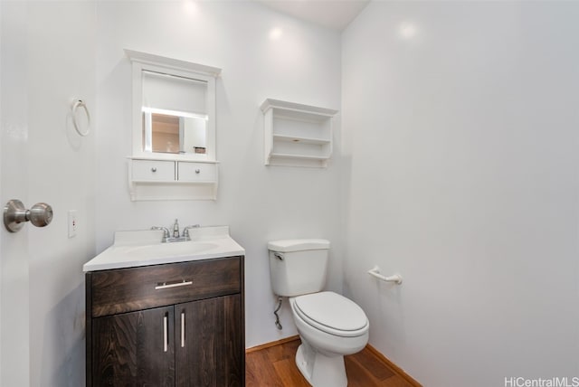 bathroom with toilet, hardwood / wood-style flooring, and vanity