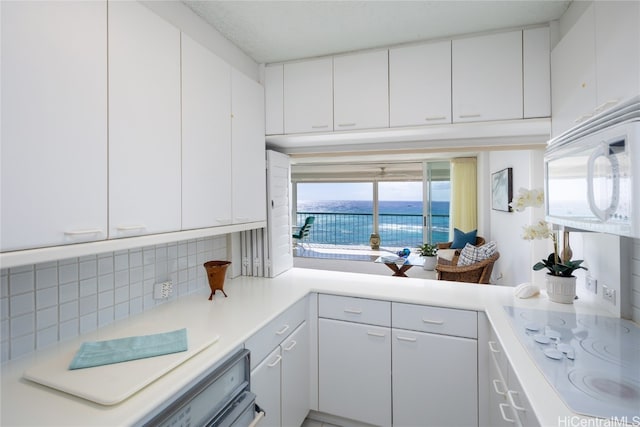 kitchen with backsplash, white cabinets, a water view, and white appliances