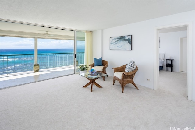 living area with carpet flooring, a water view, and ceiling fan