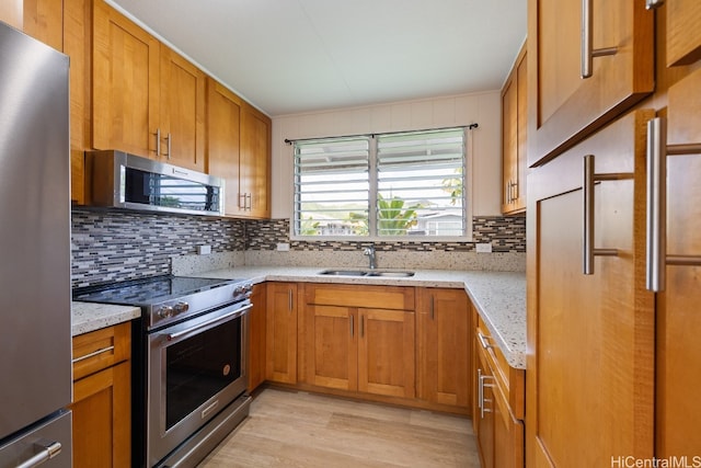 kitchen featuring light hardwood / wood-style flooring, stainless steel appliances, sink, and light stone counters