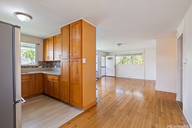 kitchen with light hardwood / wood-style flooring, backsplash, and white refrigerator