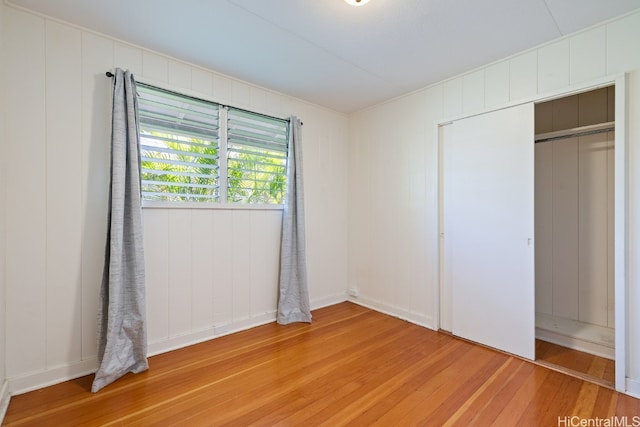 unfurnished bedroom featuring a closet, wooden walls, and hardwood / wood-style floors