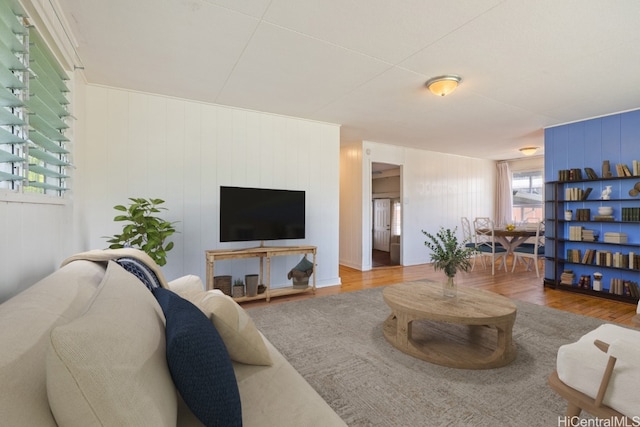 living room featuring a wealth of natural light, wood-type flooring, and wood walls