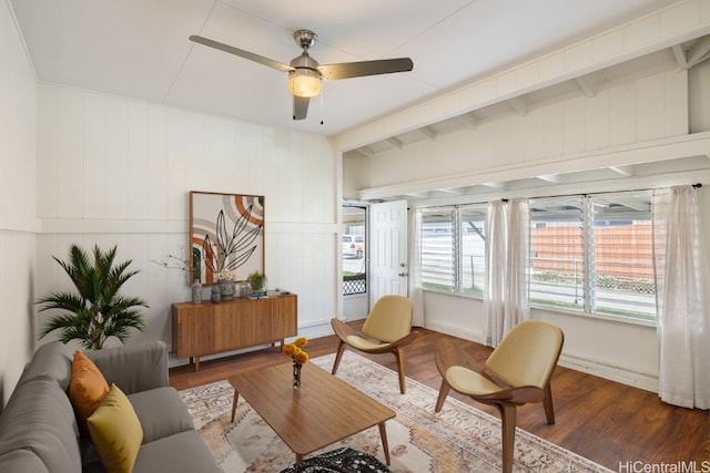 living room with wood walls, dark hardwood / wood-style floors, beamed ceiling, and ceiling fan