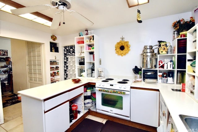 kitchen with tile patterned flooring, kitchen peninsula, electric stove, white cabinetry, and ceiling fan