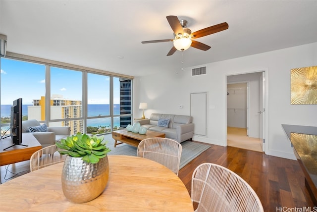 dining area featuring a water view, ceiling fan, a wealth of natural light, and dark hardwood / wood-style flooring